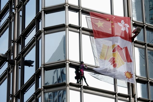 Prancūzas „žmogus voras“ su taikos plakatu užkopė į Honkongo dangoraižį 