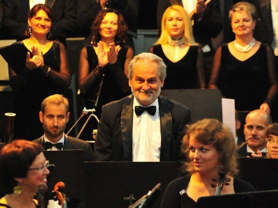 R.Giedraitis (centre) kuria muziką ir groja fleita orkestre.