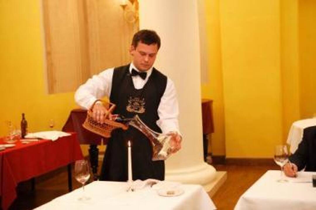 Ritualas: A. Darasevičius rengiasi dekantuoti vyną, t.y., perpilti jį iš butelio į stiklinį grafiną – dekanterį.